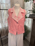 A pink sleeveless vest with a textured, distressed fabric and subtle floral embroidery, displayed on a white mannequin torso. The vest features a notched lapel collar and a single button closure.