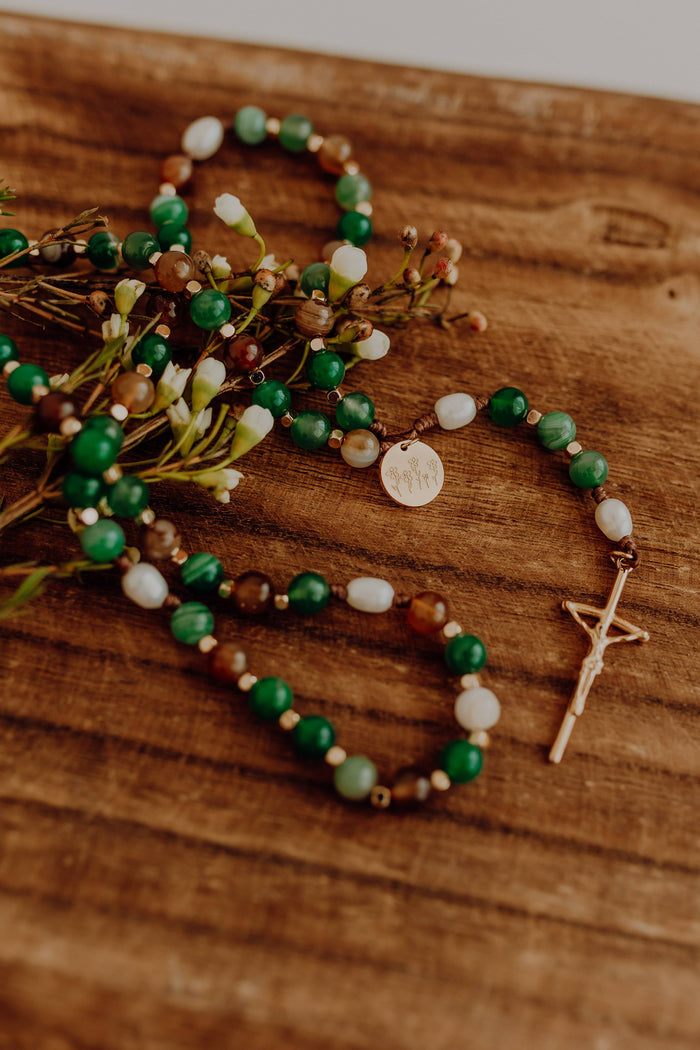 Green white and brown rosary with wooden background
