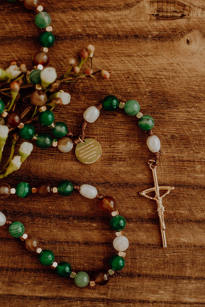 Green white and brown rosary with wooden background