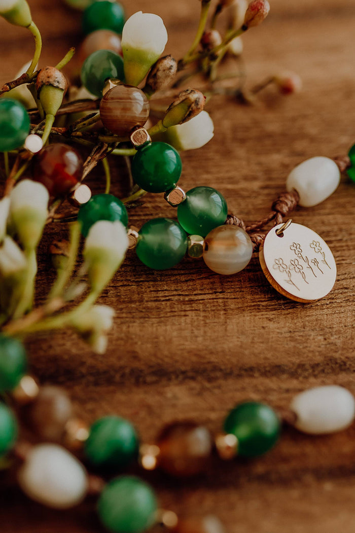 Green white and brown rosary with wooden background