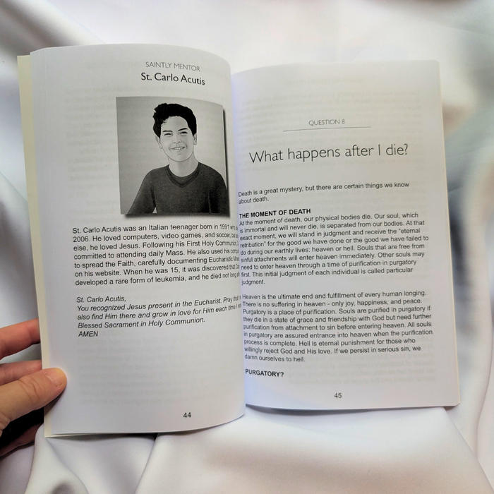 Open book with a page featuring a person and text, held by a hand.