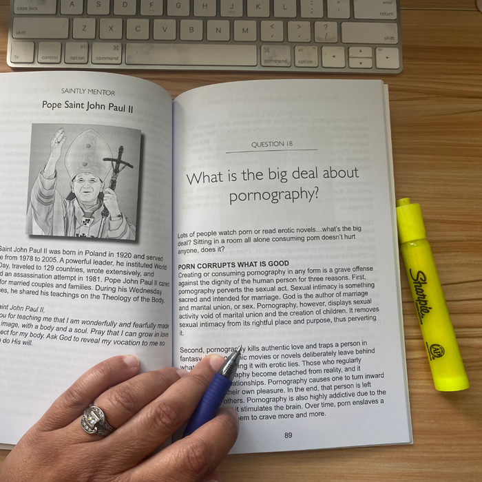 Open book with a question about pornography, a hand holding a pen, and a yellow highlighter on a wooden surface.