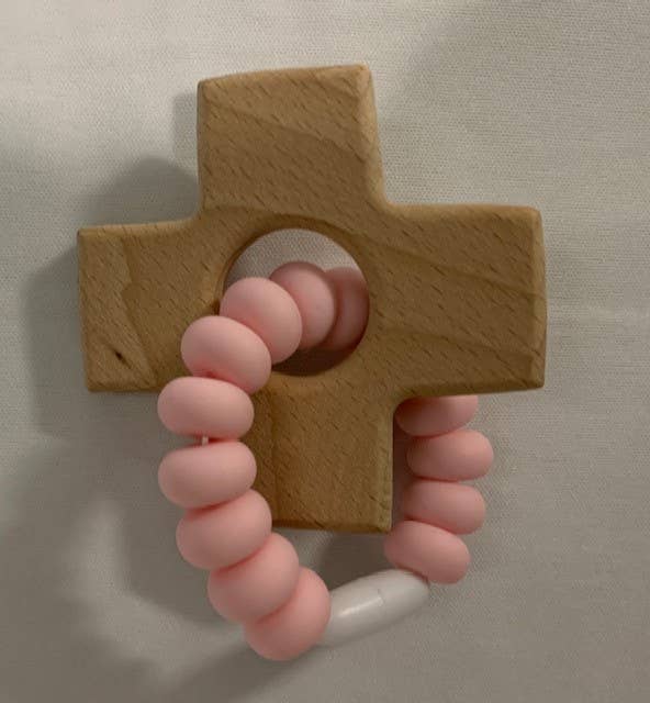 Wooden cross-shaped teether with pink silicone handle on a neutral background