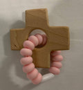 Wooden cross-shaped teether with pink silicone handle on a neutral background