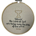 Embroidery hoop with a religious design and text on a white background