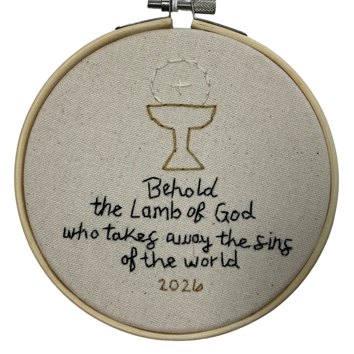 Embroidery hoop with a religious design and text on a white background