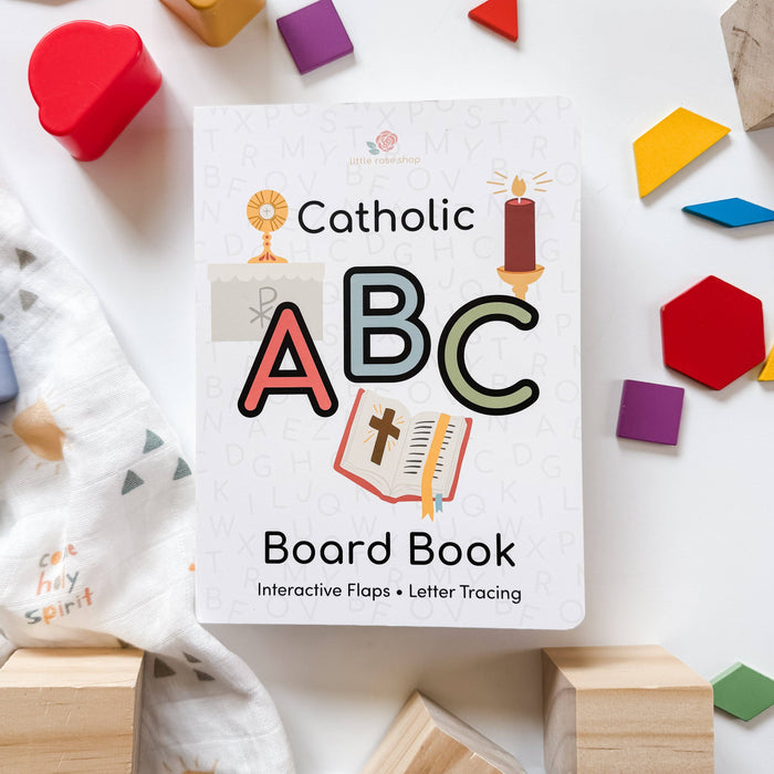 Catholic ABC Board Book surrounded by colorful blocks and toys on a white surface