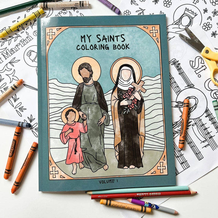 Coloring book titled 'My Saints' with illustrations of saints and children, surrounded by coloring supplies on a white background.