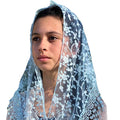 Person wearing a light blue lace veil on a white background