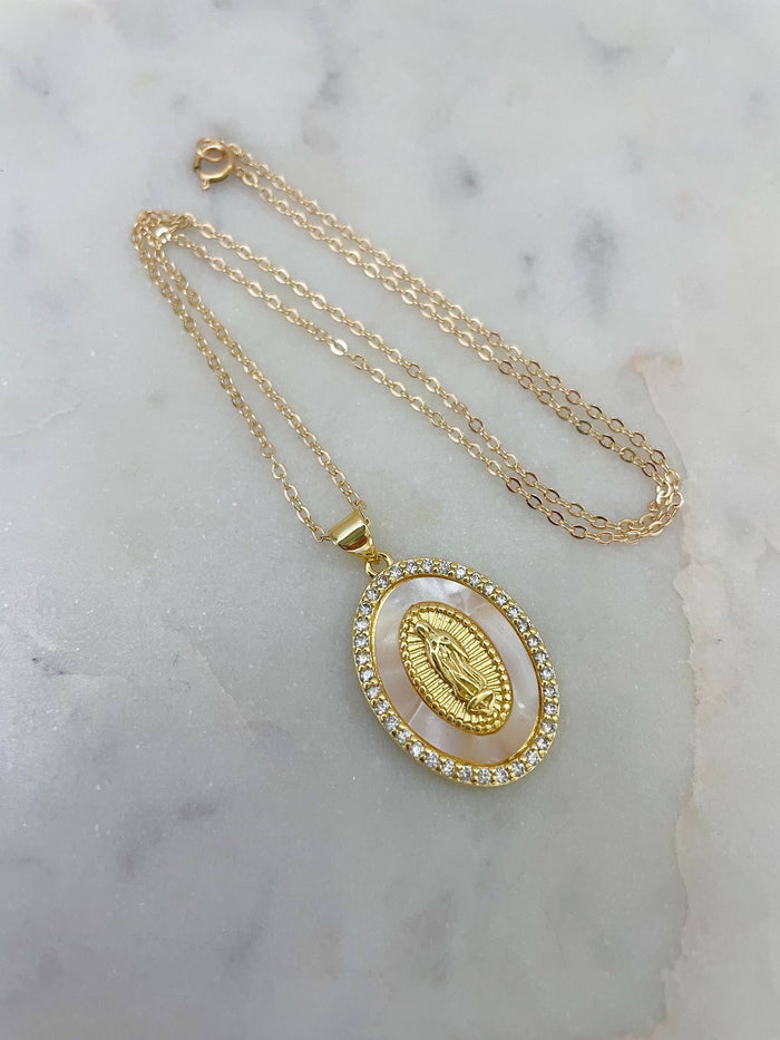 Gold necklace with a pendant on a marble surface