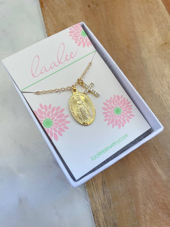 Gold necklace with a pendant on a branded card with pink flowers