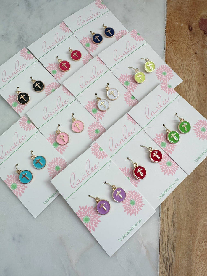 Set of earrings on branded cards with a floral design on a marble surface.
