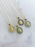 Three gold necklaces with different colored gemstone pendants on a marble surface