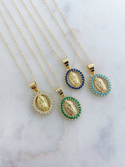 Three gold necklaces with different colored gemstone pendants on a marble surface