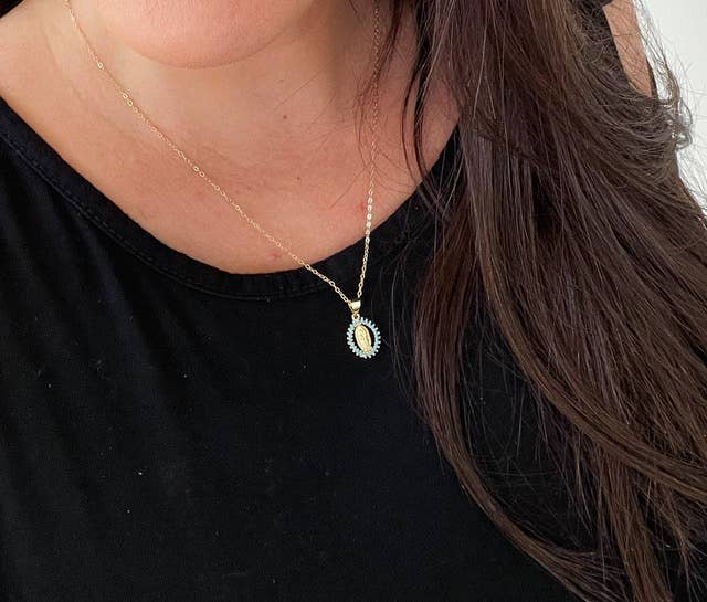 Close-up of a necklace with a pendant on a person wearing a black top.