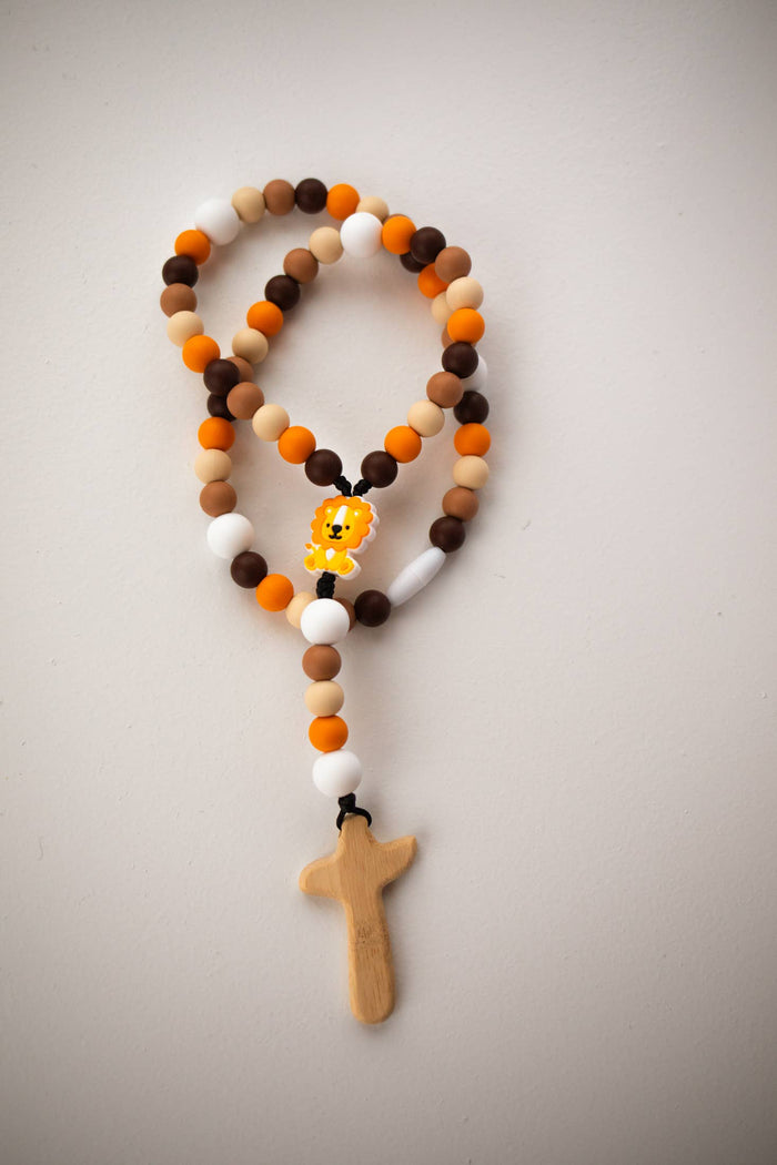 Rosary with multicolored beads and a wooden cross on a light gray background