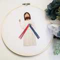 Embroidery of Jesus in an embroidery hoop on a white background.