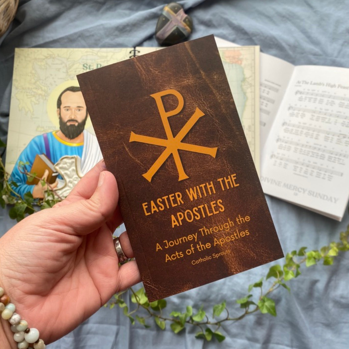 Hand holding a brown book titled 'Easter with the Apostles' on a blue fabric background.