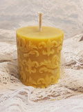 Decorative beeswax candle with intricate patterns on a lace fabric background