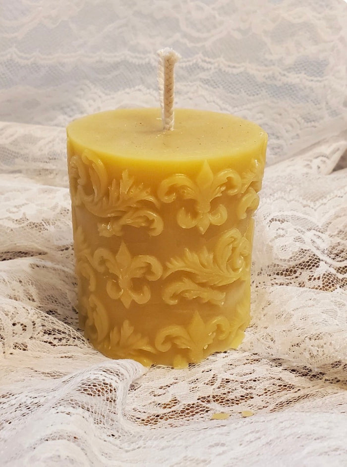 Decorative beeswax candle with intricate patterns on a lace fabric background