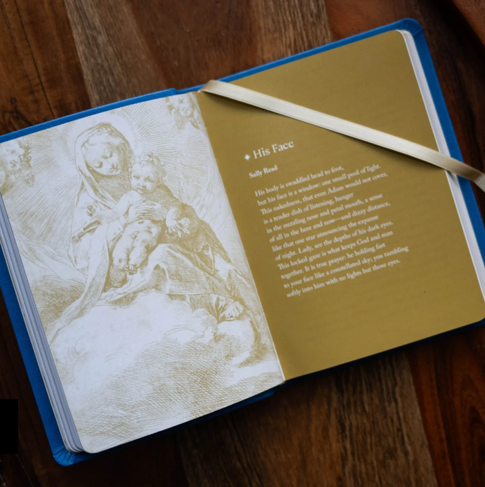 Book opened to page with Mary and baby Jesus with gold design and text
