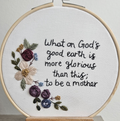 Embroidery hoop with floral design and text on a white background