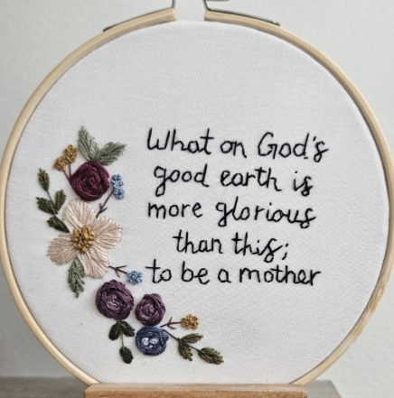 Embroidery hoop with floral design and text on a white background