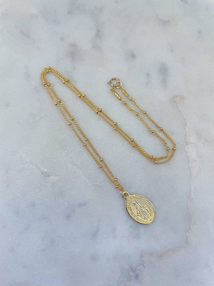 Gold necklace with a pendant on a marble surface