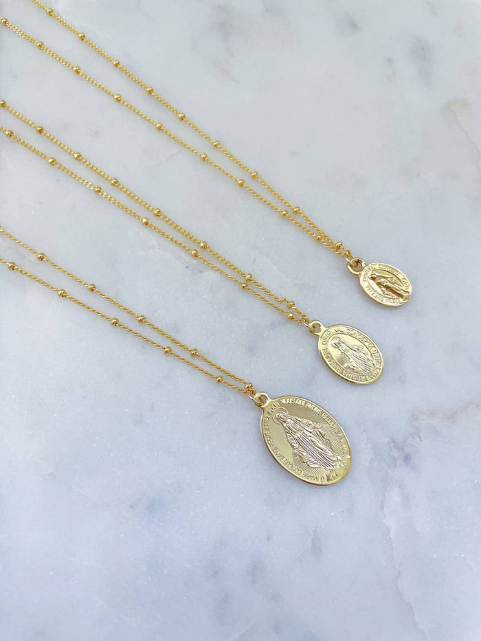 Gold necklaces with medallions on a marble surface