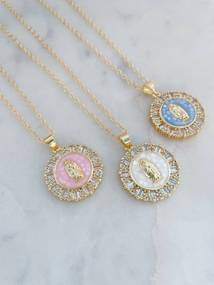 Three gold necklaces with circular pendants on a marble surface