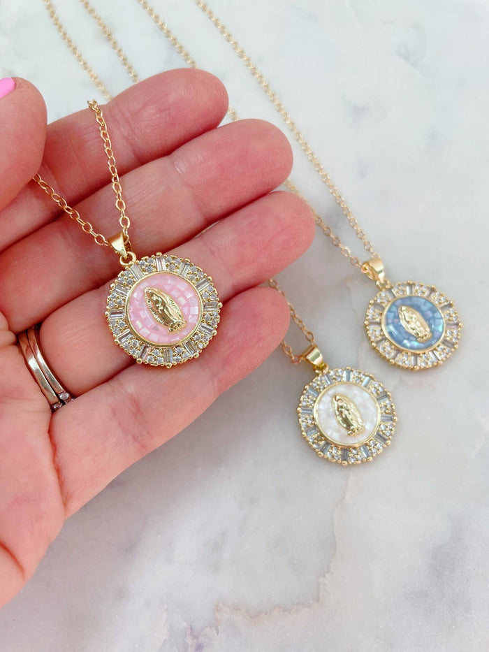 Two gold necklaces with circular pendants on a marble surface.