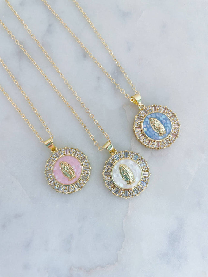 Three gold necklaces with circular pendants on a marble surface