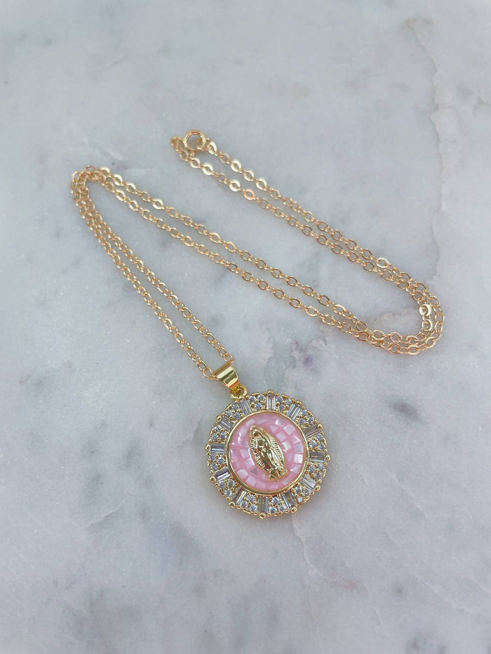 Gold necklace with a pink pendant on a marble surface