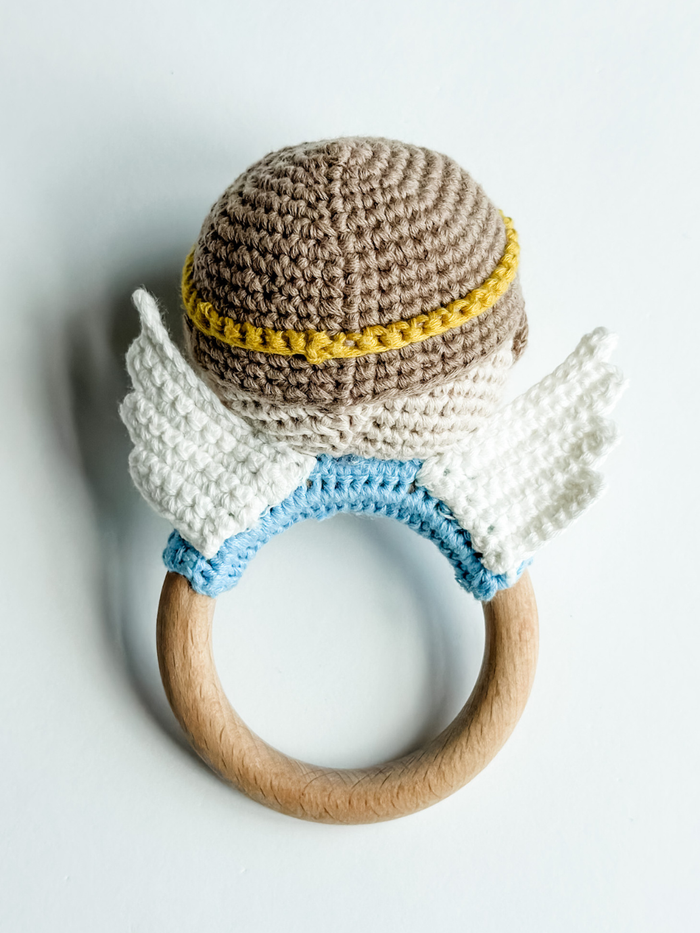 Crocheted teething ring with wooden base on a light gray background