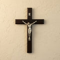Wooden cross with a silver Jesus figure on a beige wall