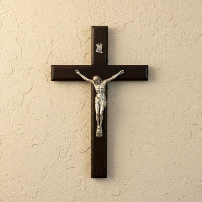 Wooden cross with a silver Jesus figure on a beige wall
