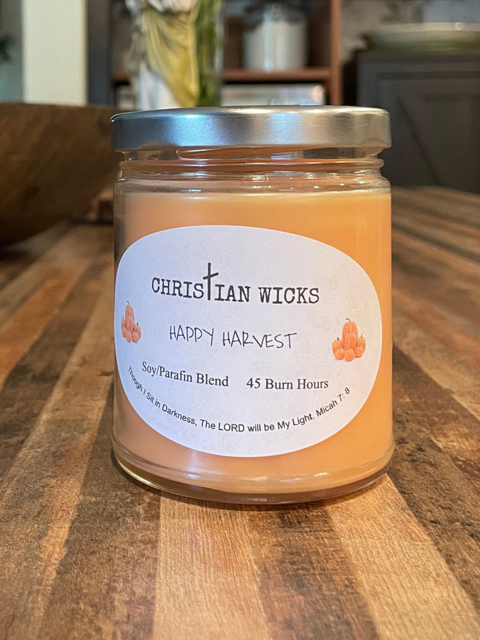 Jar of candle wax on a wooden surface with a blurred indoor background