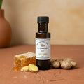 Honey Ginger White Balsamic Vinegar bottle with ginger and honeycomb on terracotta surface