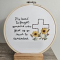 Embroidery hoop with floral design and text on a white background