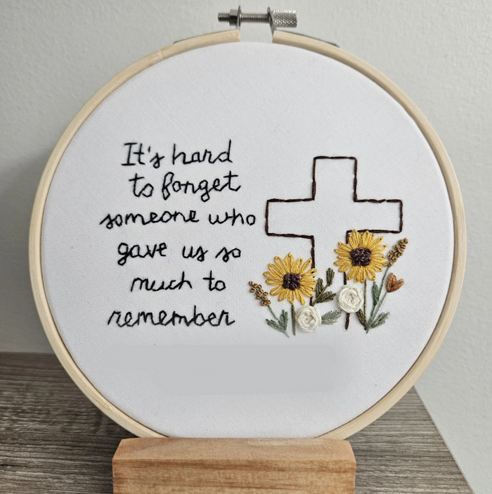 Embroidery hoop with floral design and text on a white background