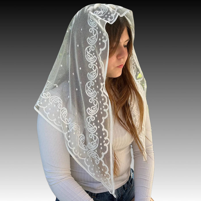 Woman wearing a white lace veil on a gray background