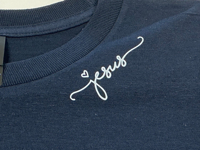 Navy blue shirt with 'Jesus' on it in white on a plain background