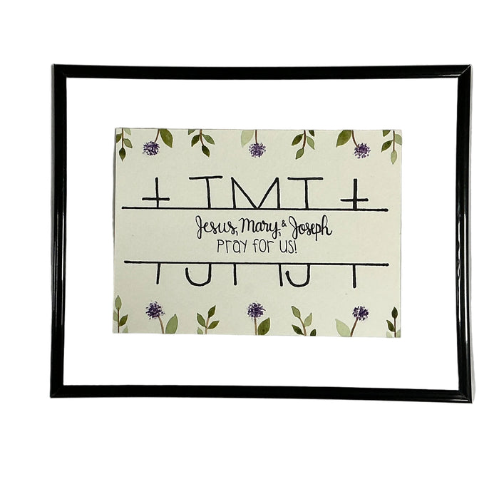 Framed artwork with 'Jesus, Mary & Joseph Pray for Us' text and floral design on a white background