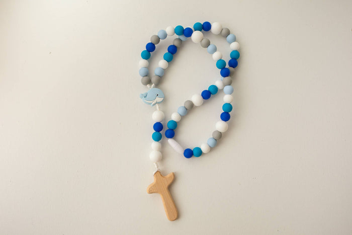 Colorful beaded rosary with a wooden cross on a light background