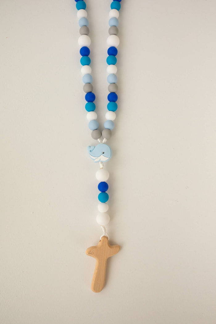 Beaded rosary with a cross and whale pendant on a plain background