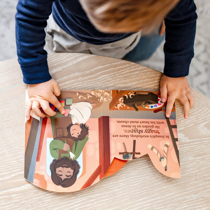 Child playing with a colorful book on a wooden table