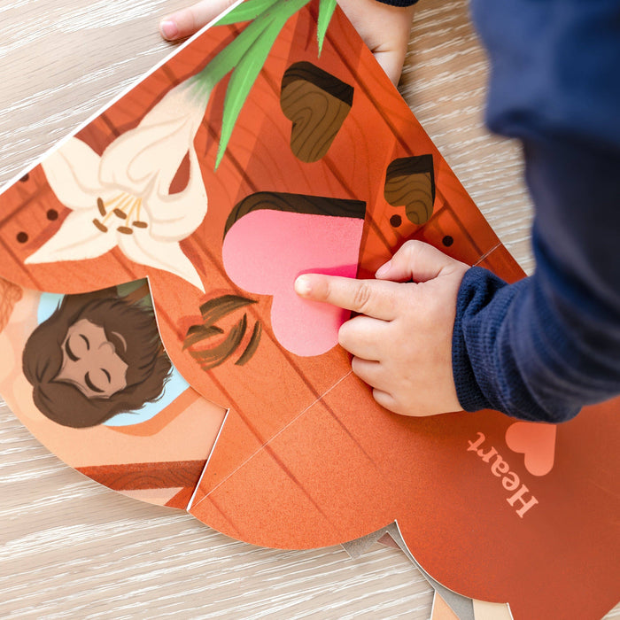 Child's hand interacting with a colorful paper craft on a wooden surface