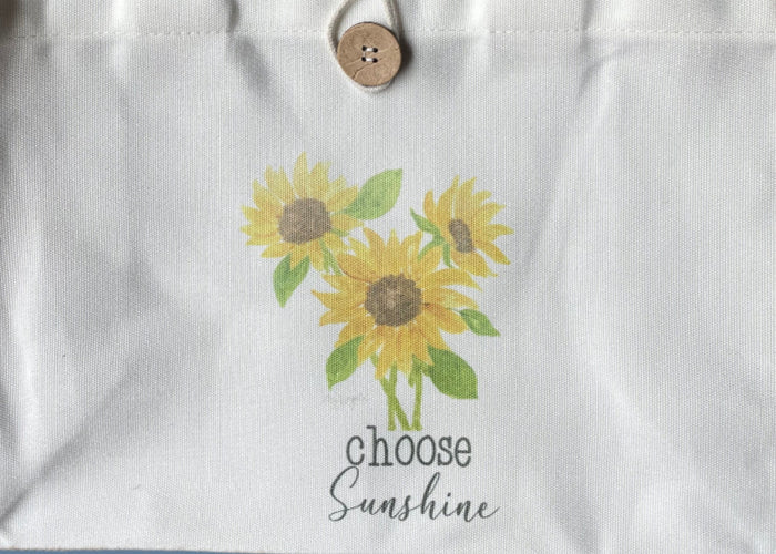 Tote bag with sunflower design and text on a blue background