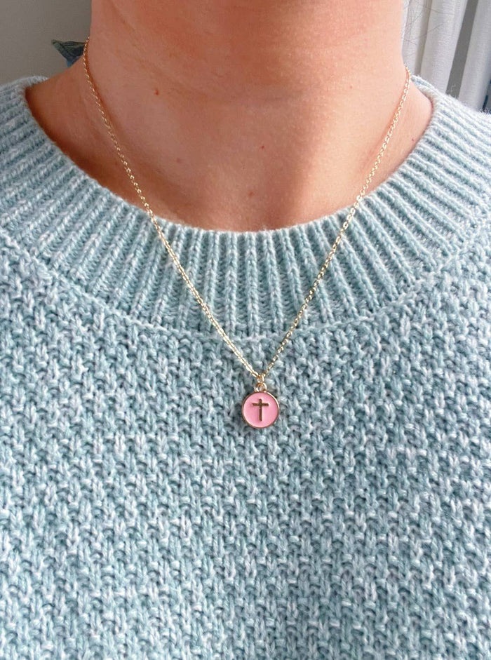Necklace with a pink pendant worn by a person in a light blue sweater.
