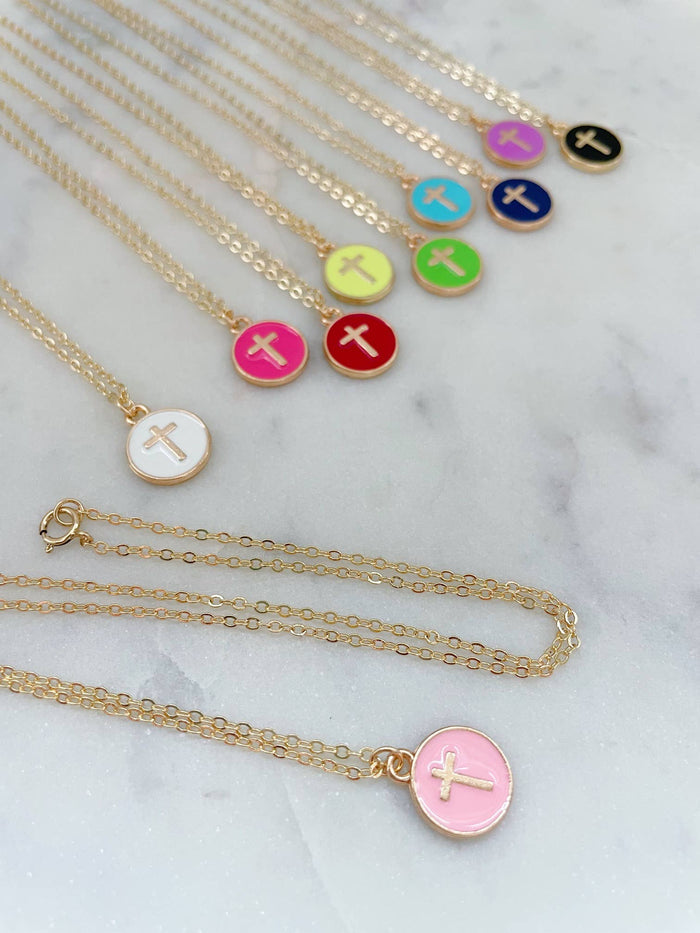 Necklaces with colorful disc pendants featuring crosses on a marble surface